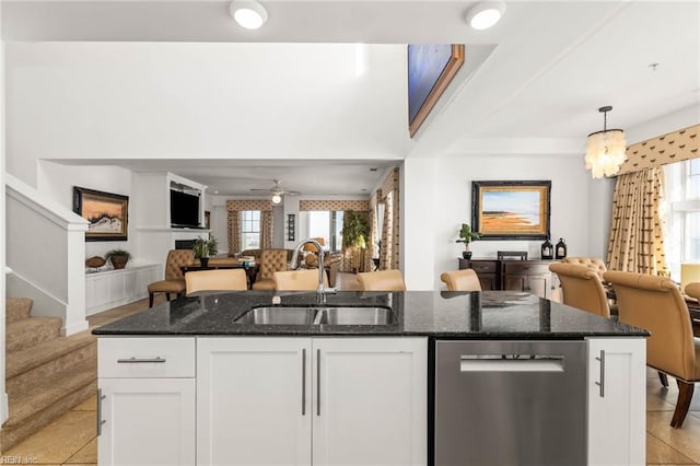 kitchen featuring white cabinets, dark stone countertops, dishwasher, pendant lighting, and sink