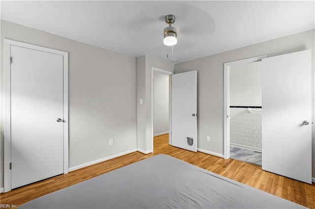 unfurnished bedroom with ceiling fan, wood-type flooring, and ensuite bath