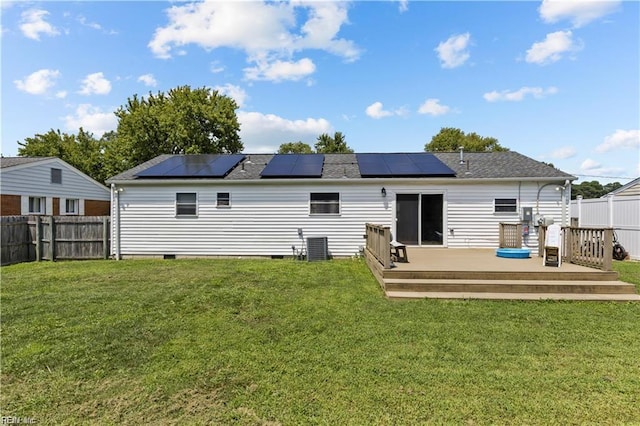 back of property featuring a lawn, solar panels, a wooden deck, and central AC