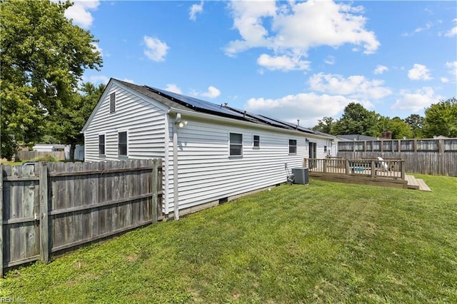 rear view of property featuring a lawn, central air condition unit, and a wooden deck