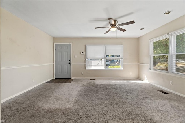 unfurnished room featuring ceiling fan, plenty of natural light, and dark colored carpet