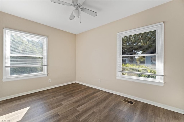 spare room with a wealth of natural light, ceiling fan, and dark hardwood / wood-style flooring