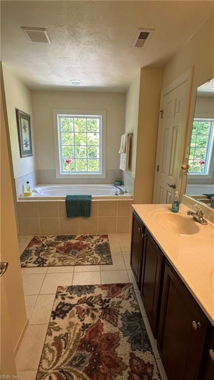 bathroom featuring vanity, tiled bath, and tile patterned flooring