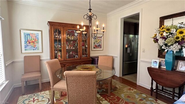 dining space featuring ornamental molding, hardwood / wood-style flooring, and a chandelier