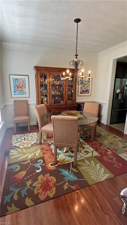 dining area featuring ornamental molding, a chandelier, and dark hardwood / wood-style flooring