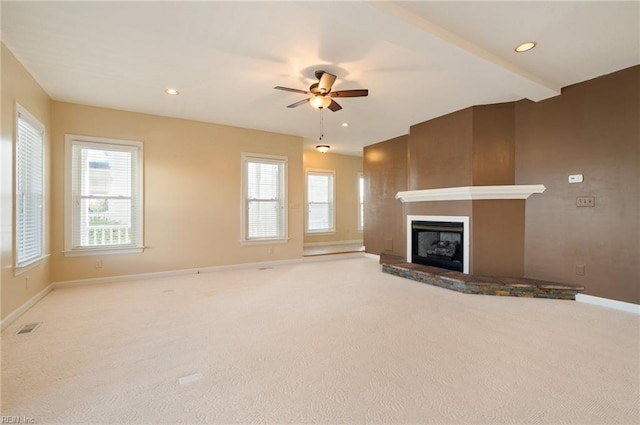 unfurnished living room featuring light carpet, beamed ceiling, a fireplace, and ceiling fan