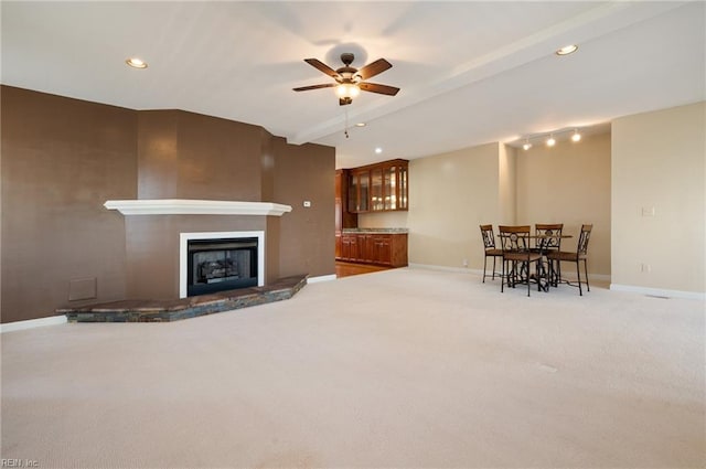 living room with ceiling fan, carpet floors, and a fireplace