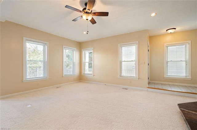 carpeted spare room featuring ceiling fan and a wealth of natural light