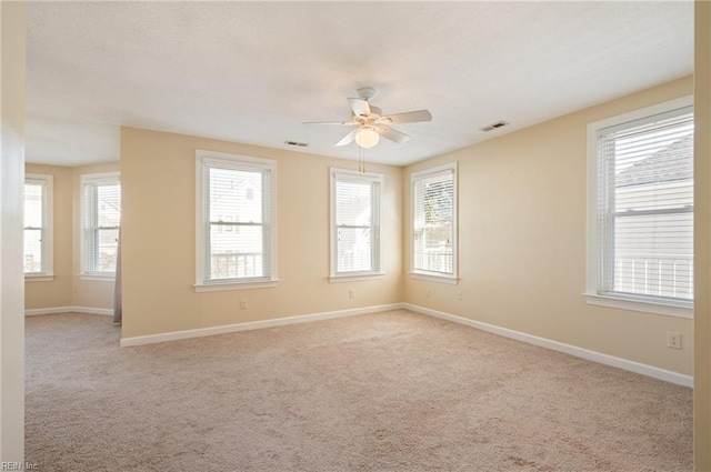 empty room featuring ceiling fan, a healthy amount of sunlight, and light colored carpet