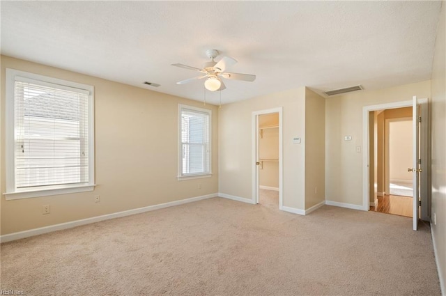 unfurnished bedroom featuring a spacious closet, multiple windows, a closet, and ceiling fan