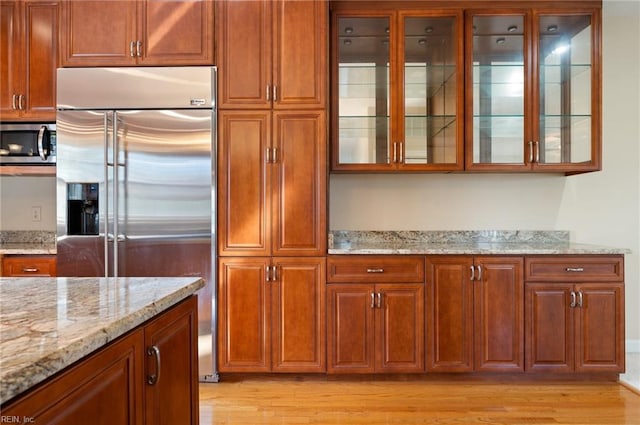 kitchen featuring light stone countertops, appliances with stainless steel finishes, and light hardwood / wood-style floors