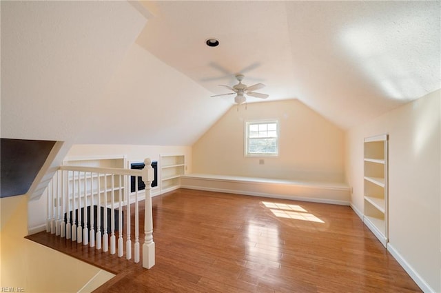 additional living space featuring vaulted ceiling, wood-type flooring, built in features, and ceiling fan