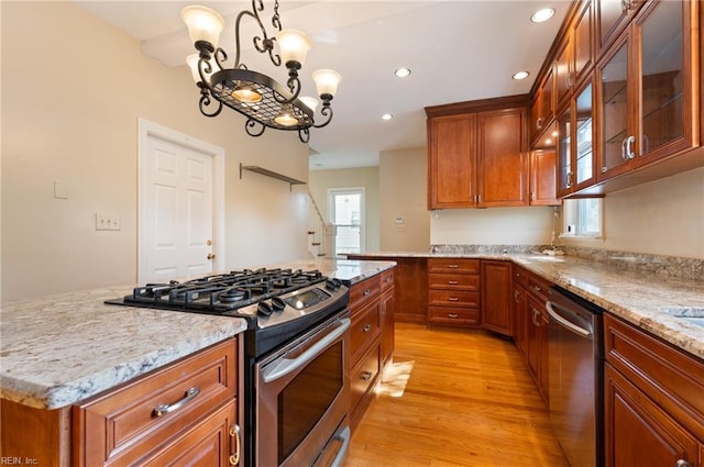 kitchen with a kitchen island, stainless steel appliances, a notable chandelier, decorative light fixtures, and light wood-type flooring