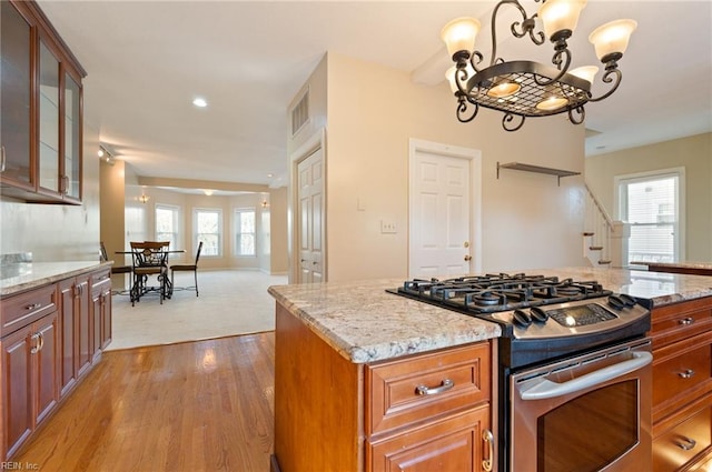 kitchen featuring light hardwood / wood-style floors, stainless steel range with gas cooktop, a wealth of natural light, and light stone counters