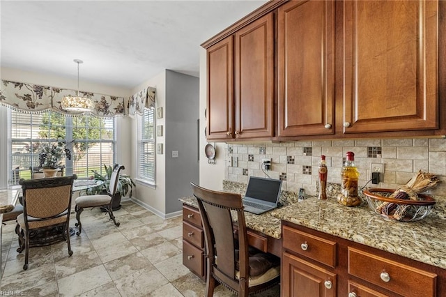 kitchen featuring an inviting chandelier, decorative light fixtures, tasteful backsplash, and light stone counters