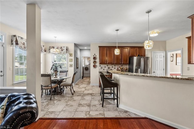 kitchen featuring hanging light fixtures, a breakfast bar, stainless steel refrigerator with ice dispenser, and light wood-type flooring