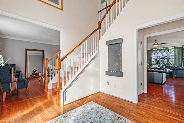 stairs with ornamental molding, hardwood / wood-style flooring, and ceiling fan