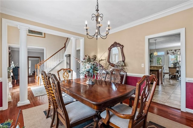 dining room with ornate columns, crown molding, hardwood / wood-style flooring, and an inviting chandelier