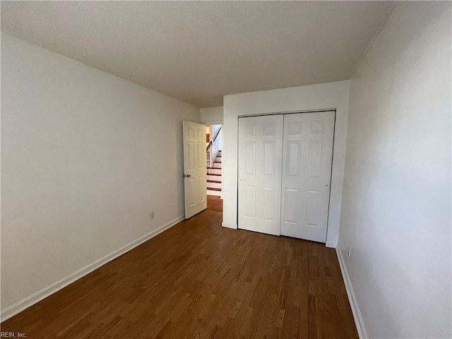 unfurnished bedroom featuring dark wood-type flooring and a closet