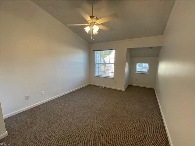 empty room featuring ceiling fan, vaulted ceiling, and dark carpet