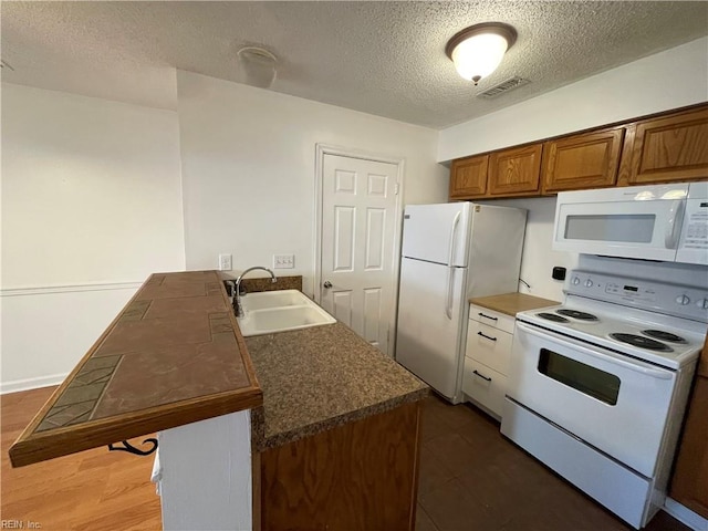 kitchen featuring white appliances, a textured ceiling, sink, and dark wood-type flooring