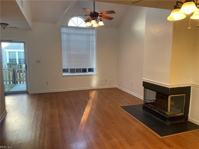 unfurnished living room with lofted ceiling, ceiling fan, a multi sided fireplace, and dark hardwood / wood-style flooring