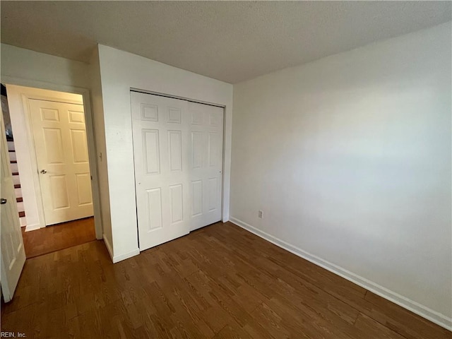 unfurnished bedroom featuring dark wood-type flooring and a closet