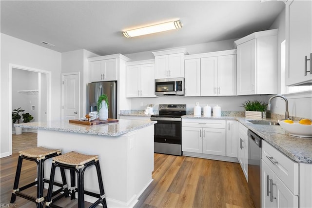 kitchen with stainless steel appliances, light hardwood / wood-style flooring, a kitchen island, and white cabinets