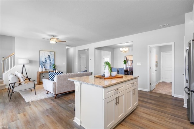 kitchen with hardwood / wood-style flooring, light stone countertops, a center island, and white cabinets