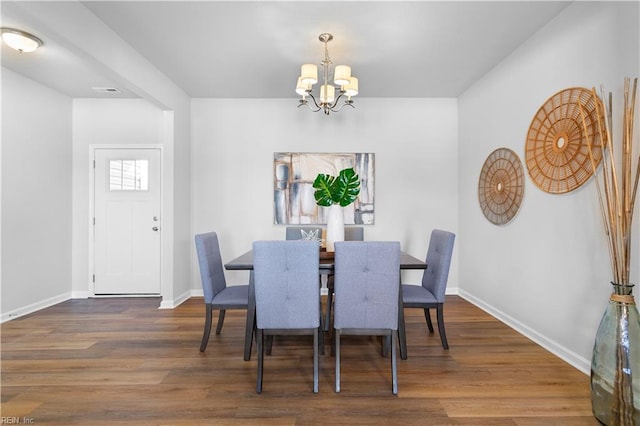 dining space with dark hardwood / wood-style floors and an inviting chandelier