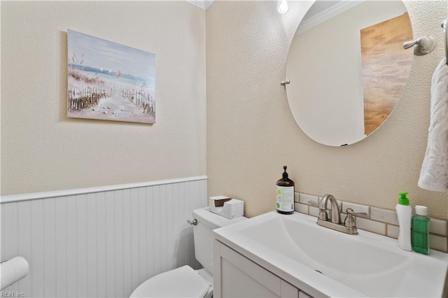 bathroom featuring toilet, ornamental molding, and vanity