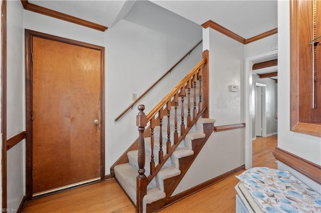 staircase featuring crown molding and wood-type flooring