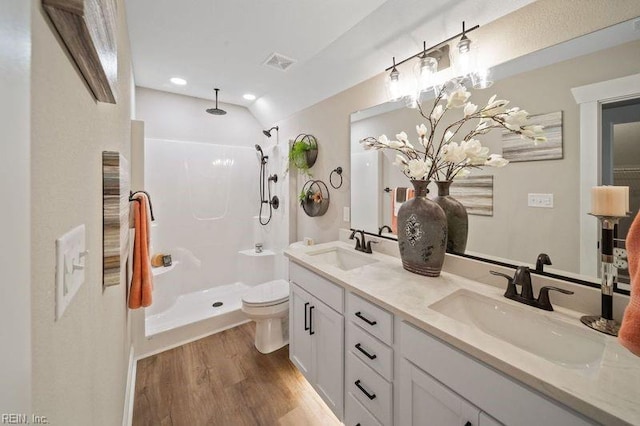 bathroom with wood-type flooring, toilet, walk in shower, vaulted ceiling, and vanity