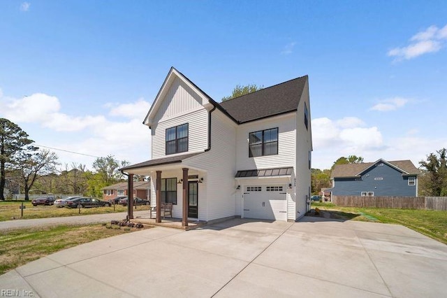 view of front of property featuring covered porch, a garage, and a front lawn