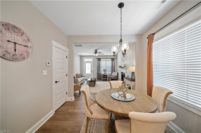 dining space featuring dark hardwood / wood-style floors and ceiling fan with notable chandelier