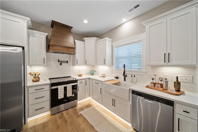 kitchen with appliances with stainless steel finishes, sink, custom exhaust hood, and white cabinets