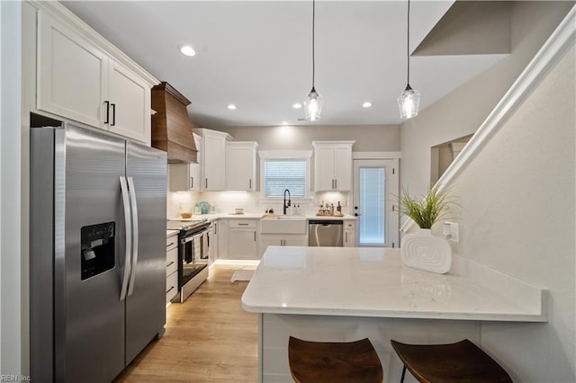 kitchen with appliances with stainless steel finishes, sink, backsplash, decorative light fixtures, and white cabinets