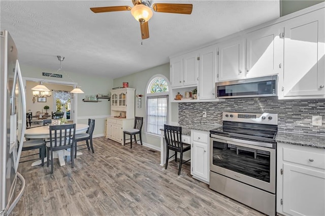 kitchen featuring appliances with stainless steel finishes, backsplash, white cabinetry, and decorative light fixtures