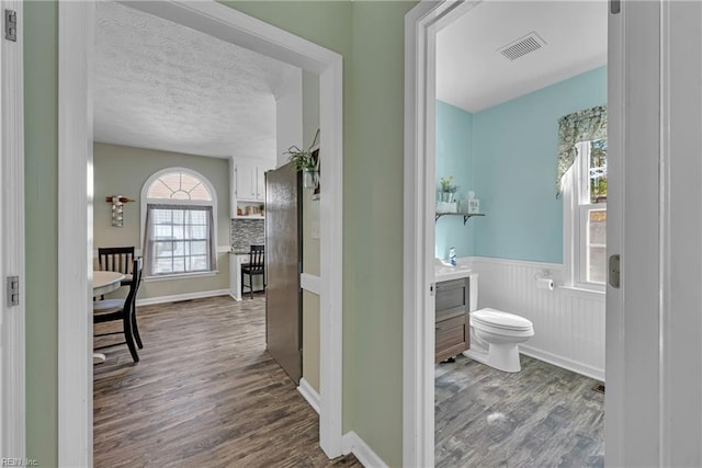 bathroom featuring toilet, a healthy amount of sunlight, hardwood / wood-style floors, and vanity