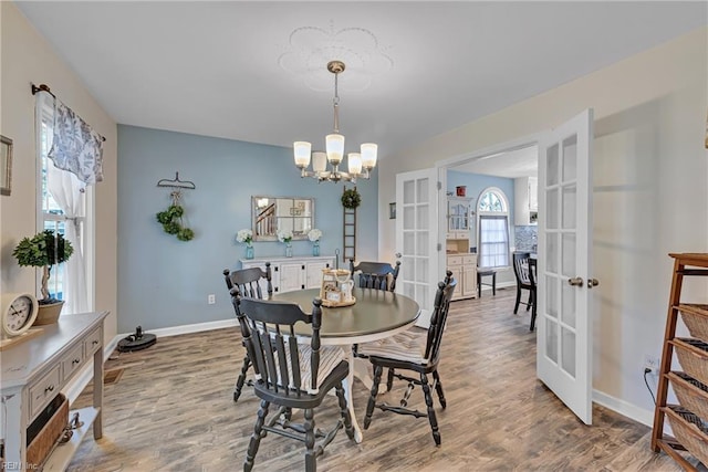 dining area with an inviting chandelier, wood-type flooring, and french doors