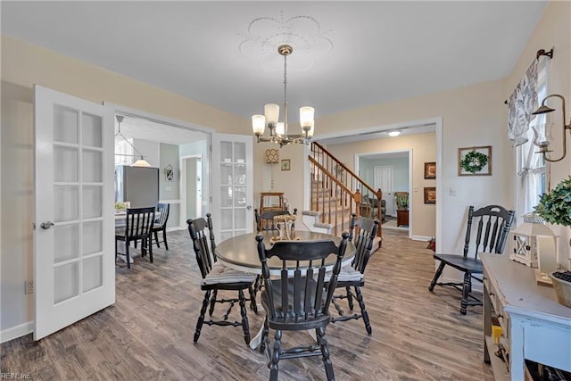 dining room featuring wood-type flooring, french doors, and a notable chandelier