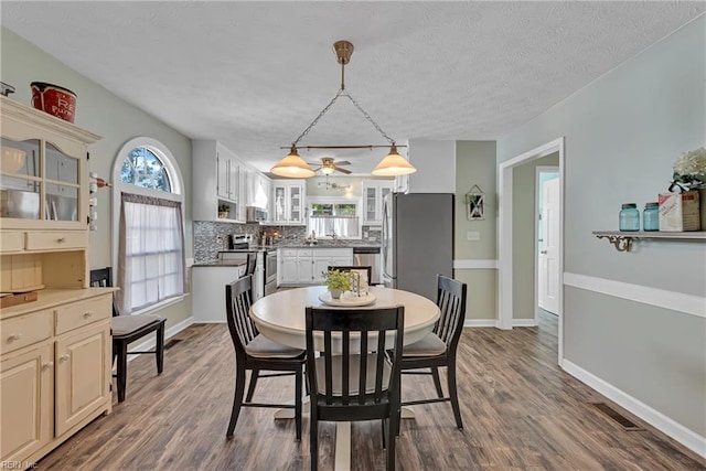 dining area with dark wood-type flooring and a textured ceiling