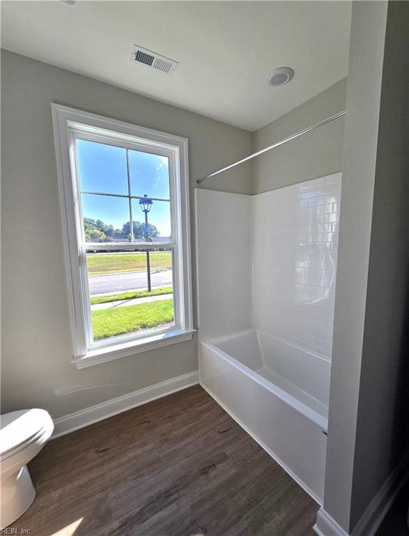 bathroom with shower / bathtub combination, wood-type flooring, toilet, and a wealth of natural light