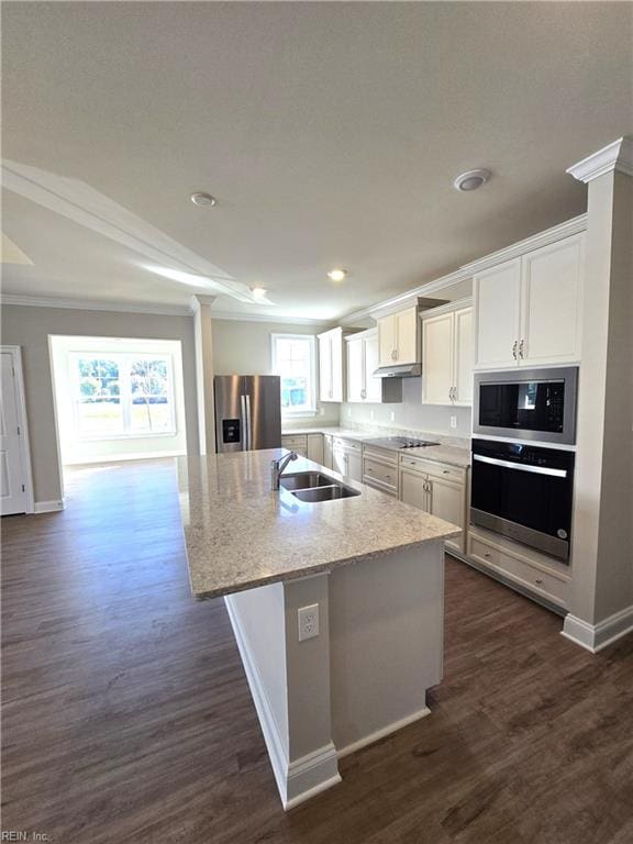 kitchen featuring light stone countertops, appliances with stainless steel finishes, a kitchen island with sink, sink, and white cabinets