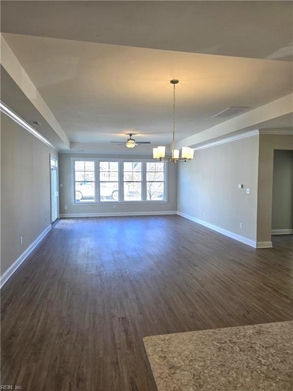 empty room featuring ceiling fan with notable chandelier, a raised ceiling, and dark wood-type flooring