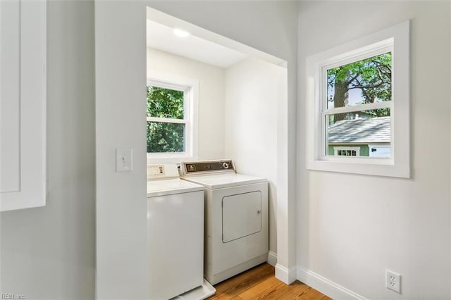 laundry area featuring washing machine and dryer, light hardwood / wood-style flooring, and plenty of natural light