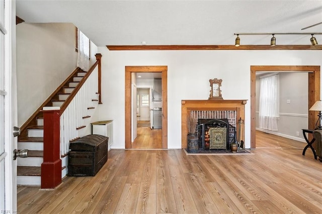 living room with track lighting, a brick fireplace, and hardwood / wood-style floors