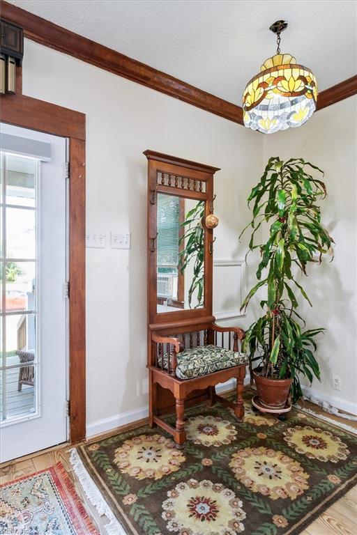 foyer entrance with crown molding and light wood-type flooring