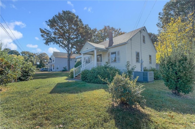 view of front of property with covered porch, cooling unit, and a front lawn