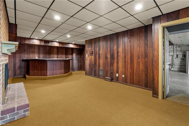 bar with light colored carpet, wooden walls, and a brick fireplace